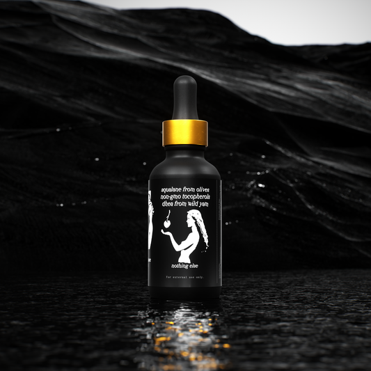 Black dropper bottle with gold cap on a black textured background